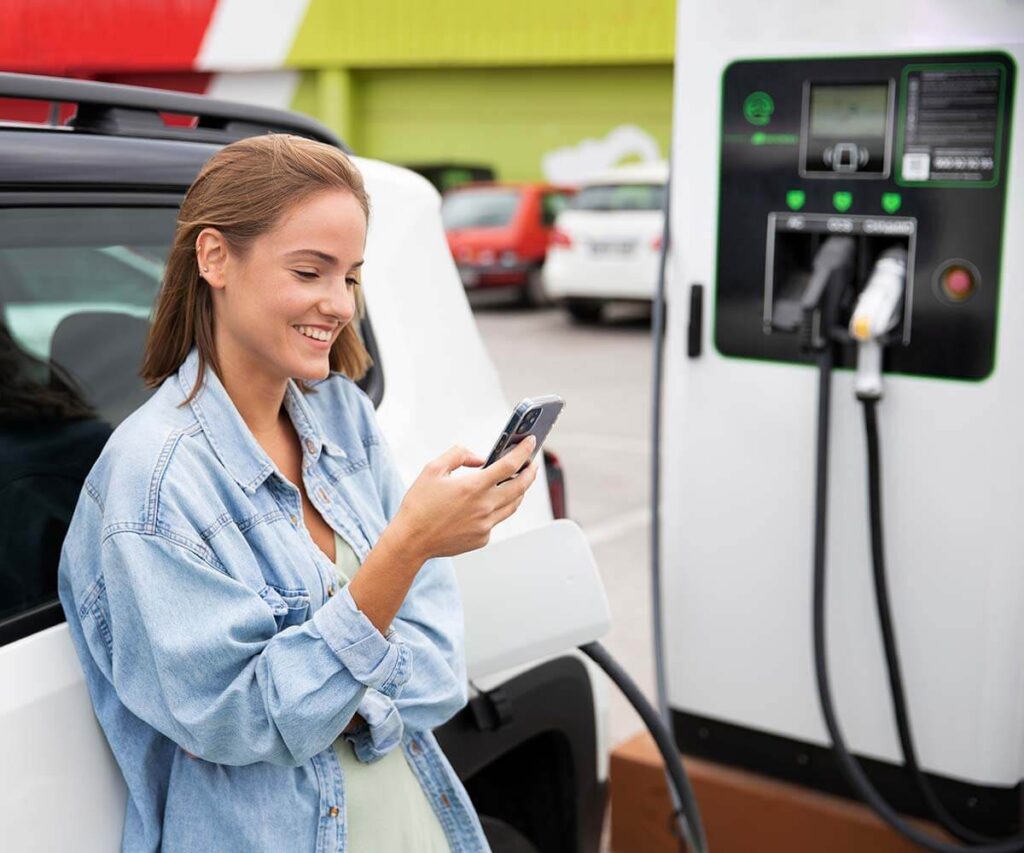 Frau schaut auf Ihr handy am E Auto